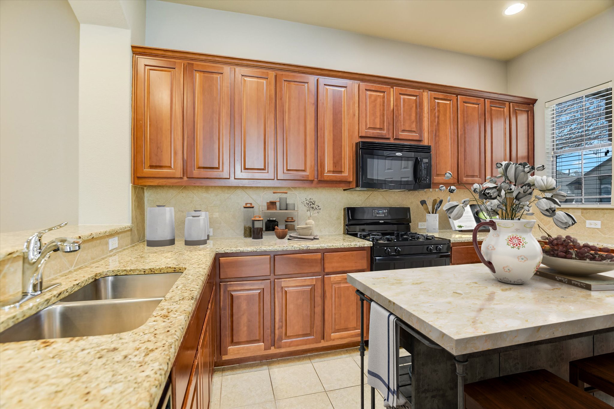 14100 Avery Ranch Boulevard, Unit 1101 Austin, TX 78717 - Photo 6 of 25 Kitchen featuring wood finish cabinets, black appliances, decorative backsplash, light tile patterned floors, and a breakfast bar