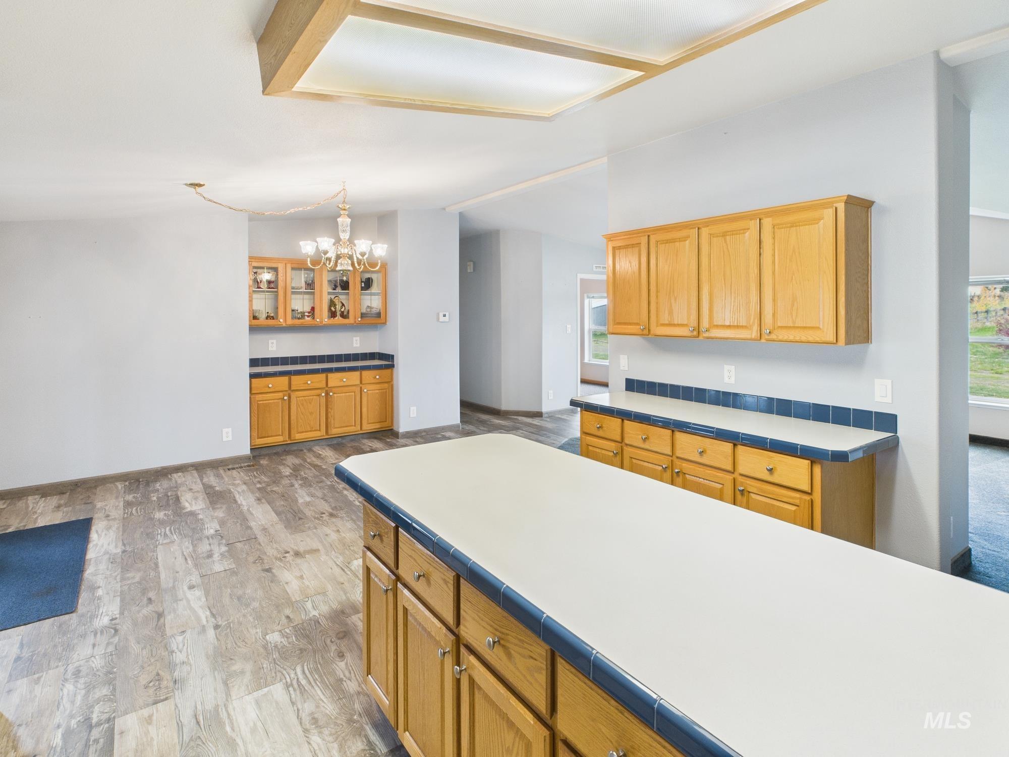 523 3rd Street Ferdinand, ID 83526 - Photo 11 of 41 Kitchen with light wood-style floors, tile countertops, a chandelier, brown cabinetry, and vaulted ceiling