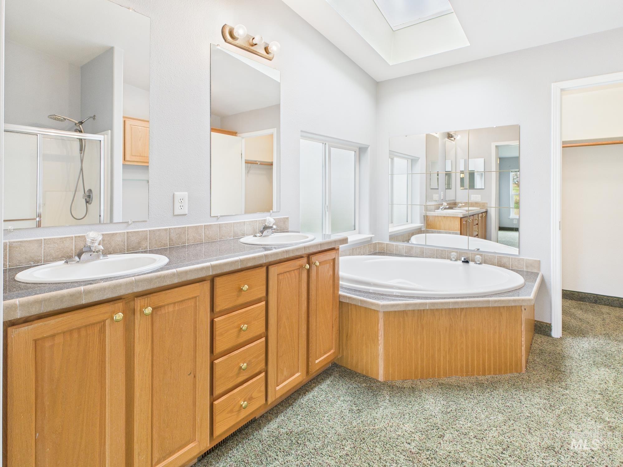 523 3rd Street Ferdinand, ID 83526 - Photo 15 of 41 Bathroom featuring a stall shower, double vanity, a bath, a skylight, and a closet