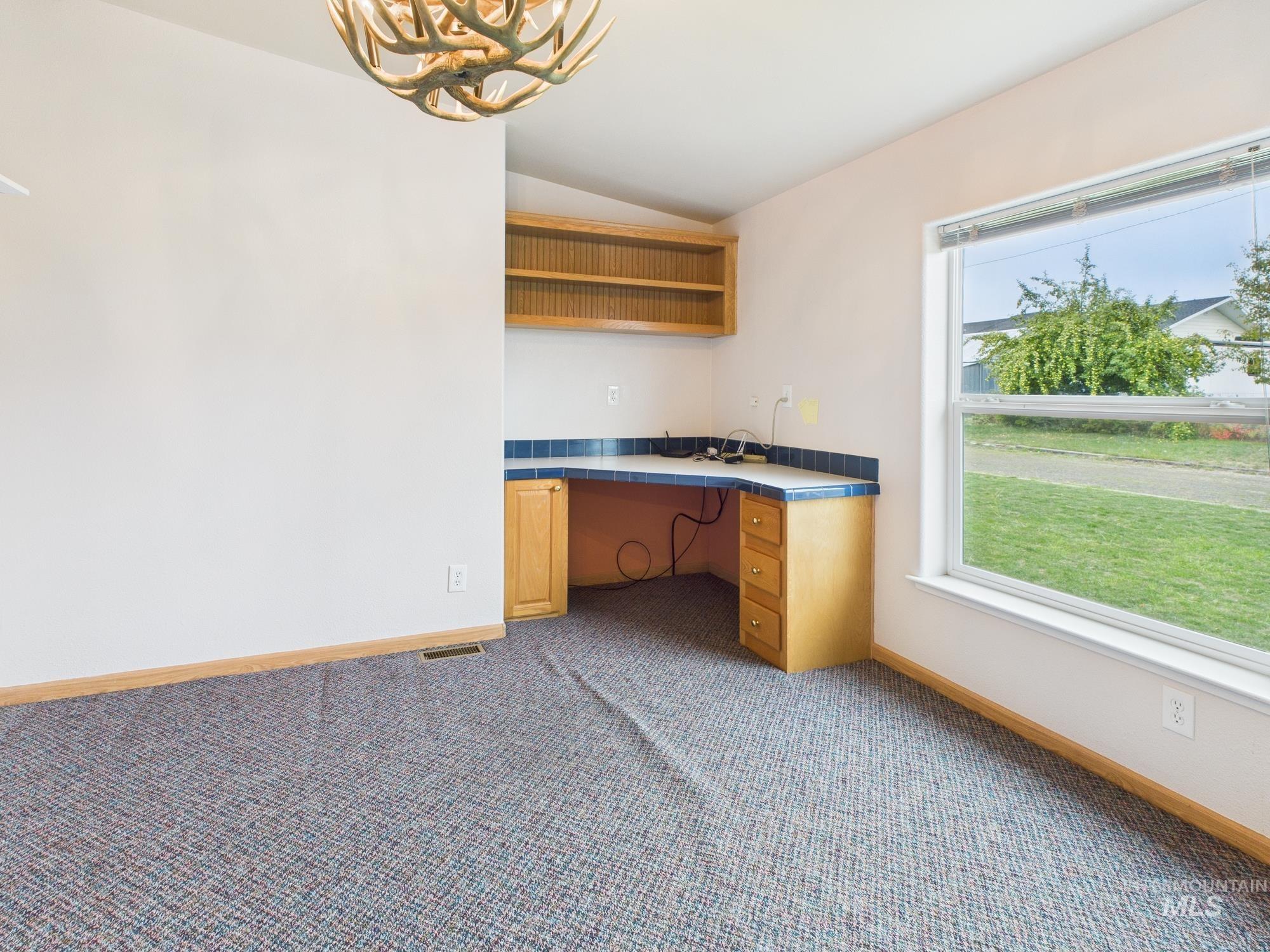 523 3rd Street Ferdinand, ID 83526 - Photo 16 of 41 Unfurnished office with built in desk, vaulted ceiling, dark carpet, and a chandelier