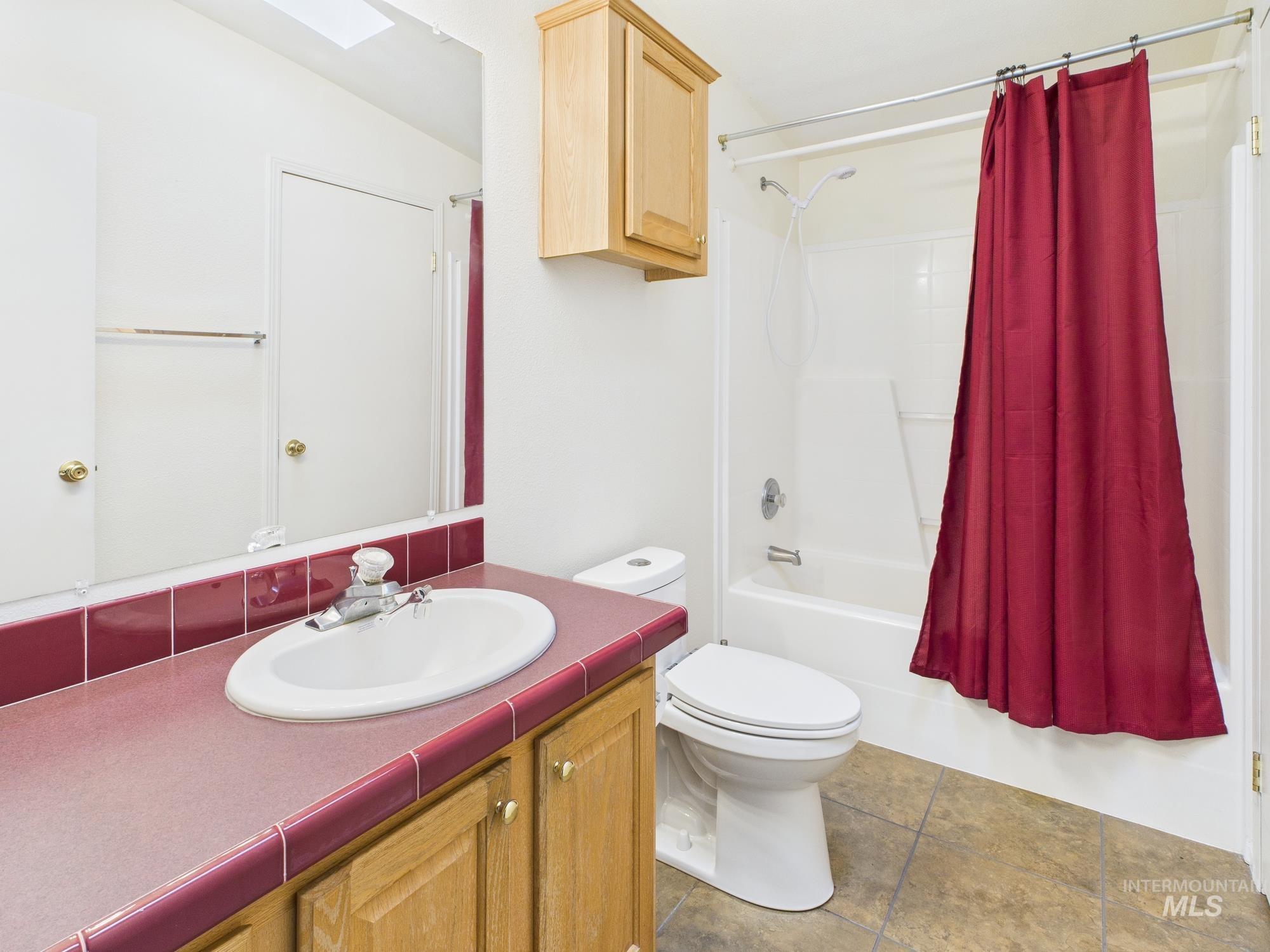 523 3rd Street Ferdinand, ID 83526 - Photo 21 of 41 Full bathroom with shower / bath combo with shower curtain, a skylight, vanity, and light tile patterned flooring