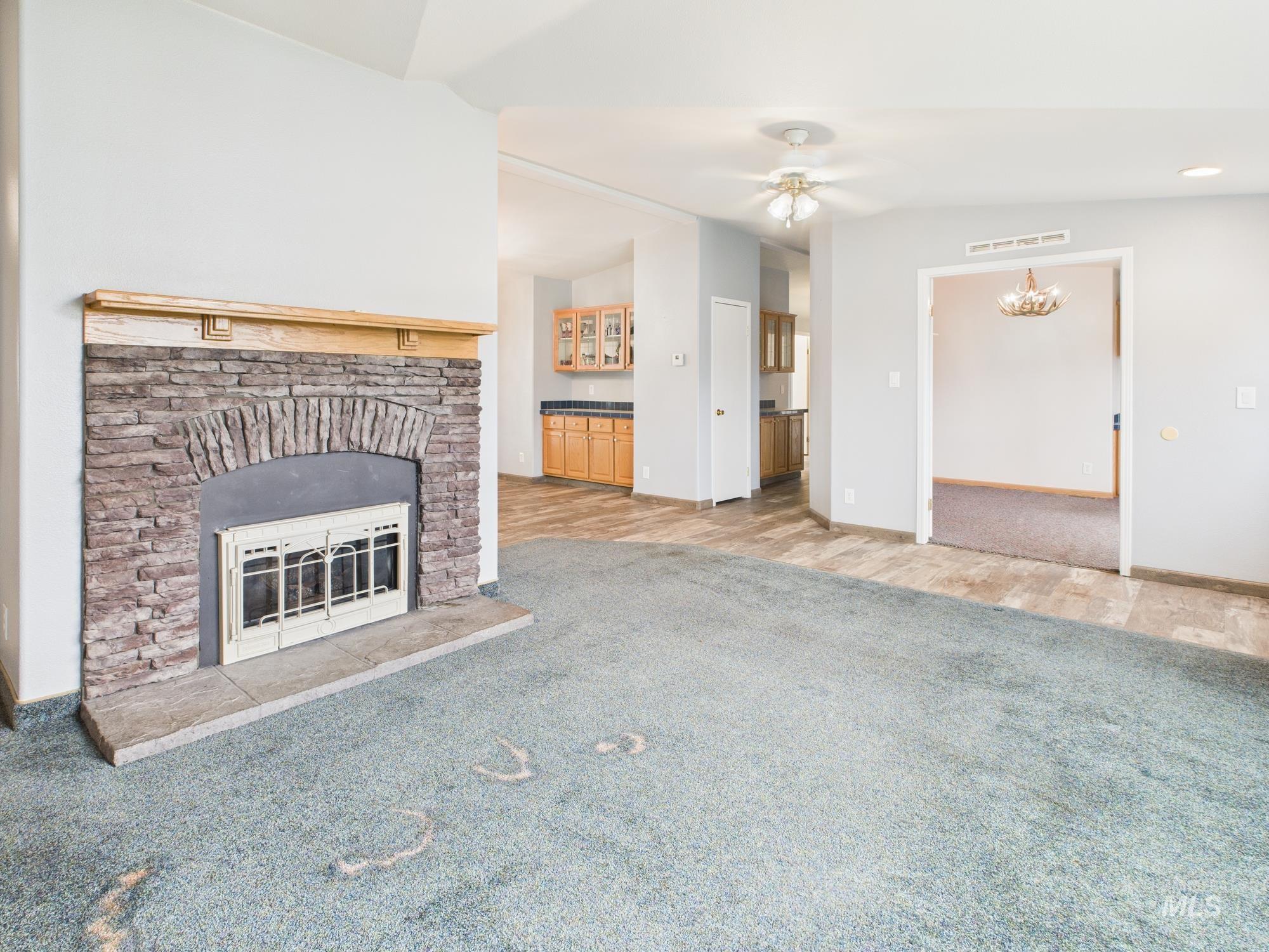 523 3rd Street Ferdinand, ID 83526 - Photo 6 of 41 Unfurnished living room featuring carpet floors, a fireplace, a ceiling fan, vaulted ceiling, and a chandelier