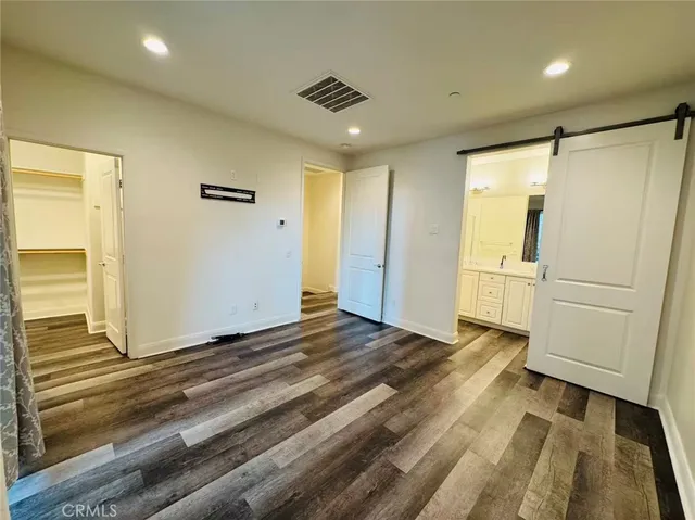 a view of an empty room with wooden floor and closet