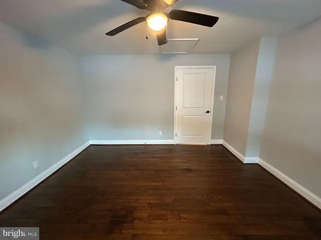 a view of an empty room with wooden floor and a ceiling fan