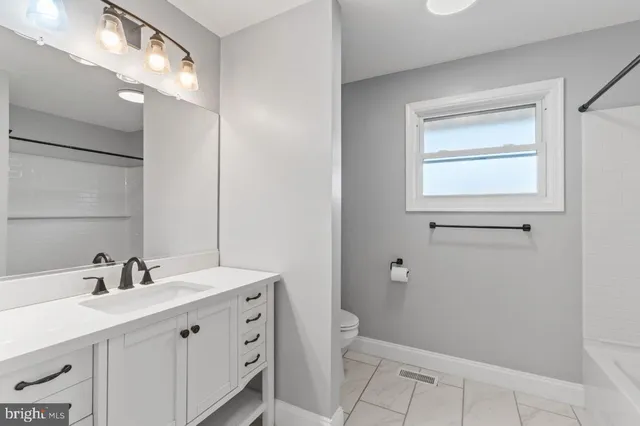 a bathroom with a double vanity sink a toilet and a mirror