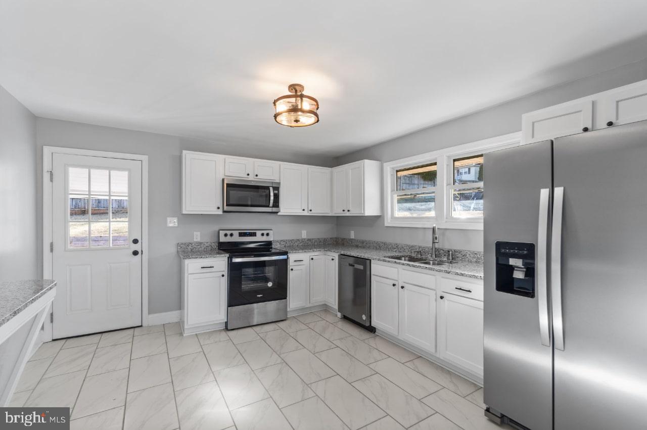 354 Berry Street Orange, VA 22960 - Photo 5 of 31 a kitchen with stainless steel appliances granite countertop a refrigerator oven a sink dishwasher and white cabinets with wooden floor