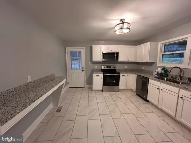 a large kitchen with granite countertop a stove a sink and a microwave