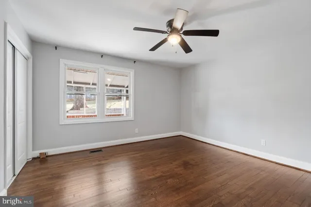 an empty room with wooden floor fan and windows