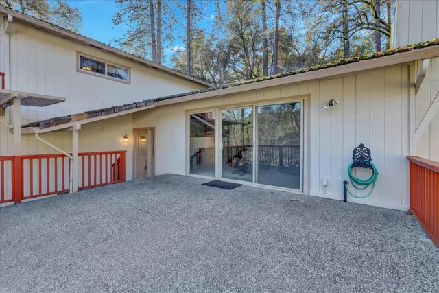 a view of a patio with table and chairs under an umbrella with large trees