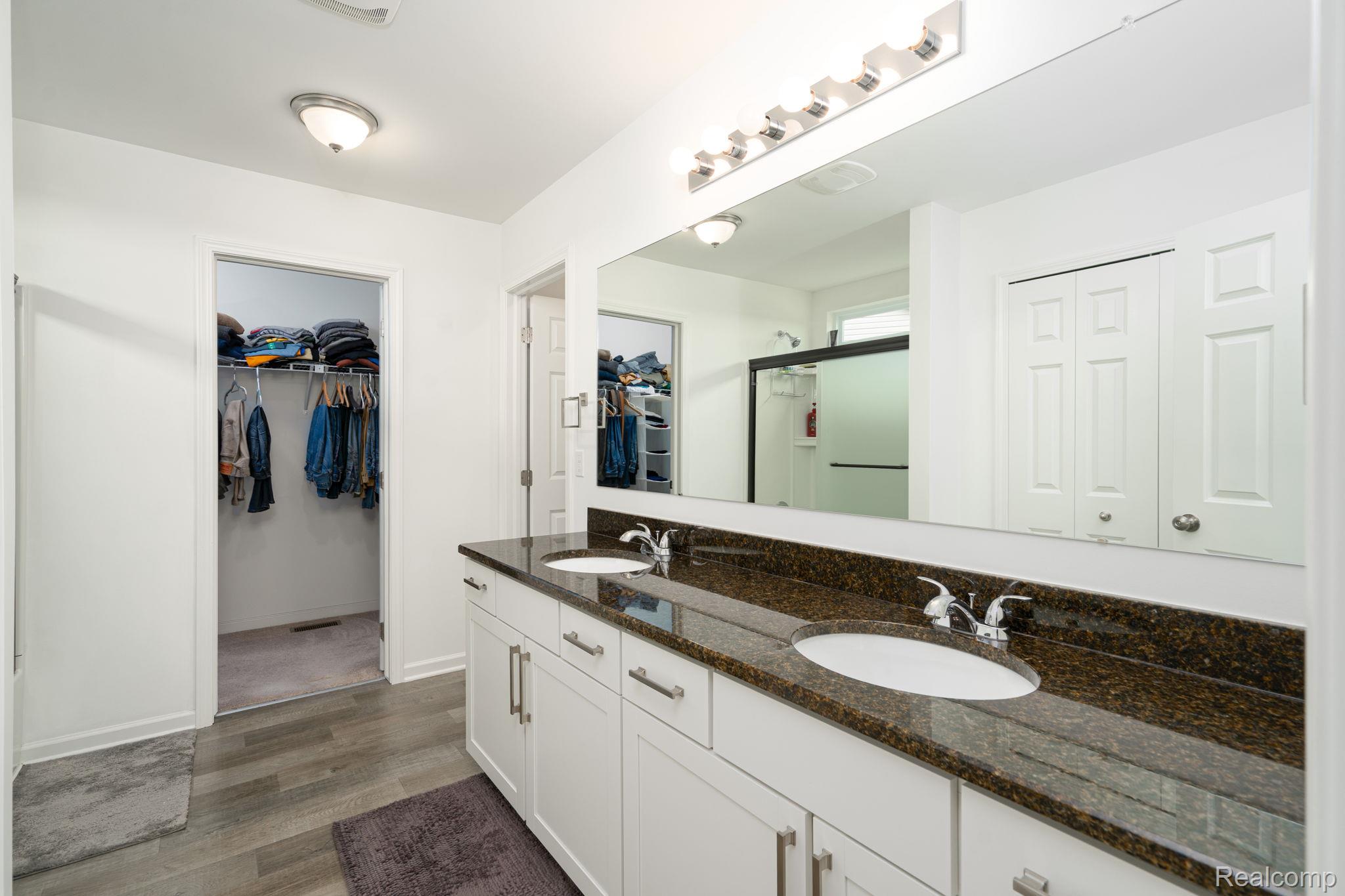 48904 Carnegie Way Macomb, MI 48042 - Photo 23 of 34 Bathroom featuring a dual vanity with a dark stone countertop, white cabinetry, and chrome fixtures
