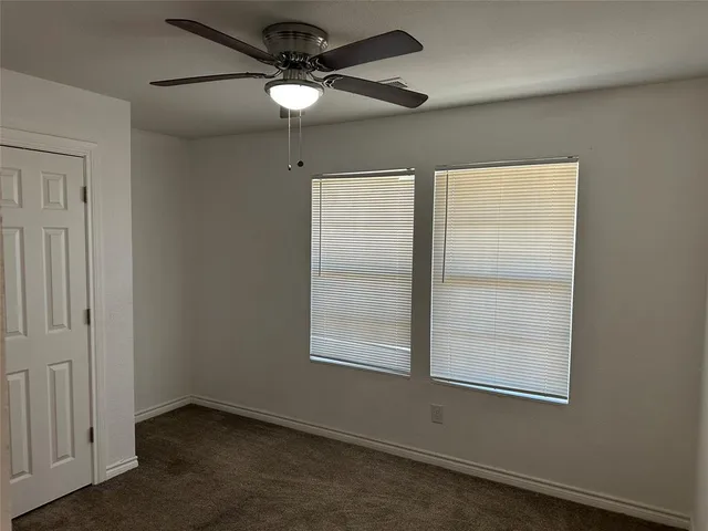 an empty room with a window and a fan