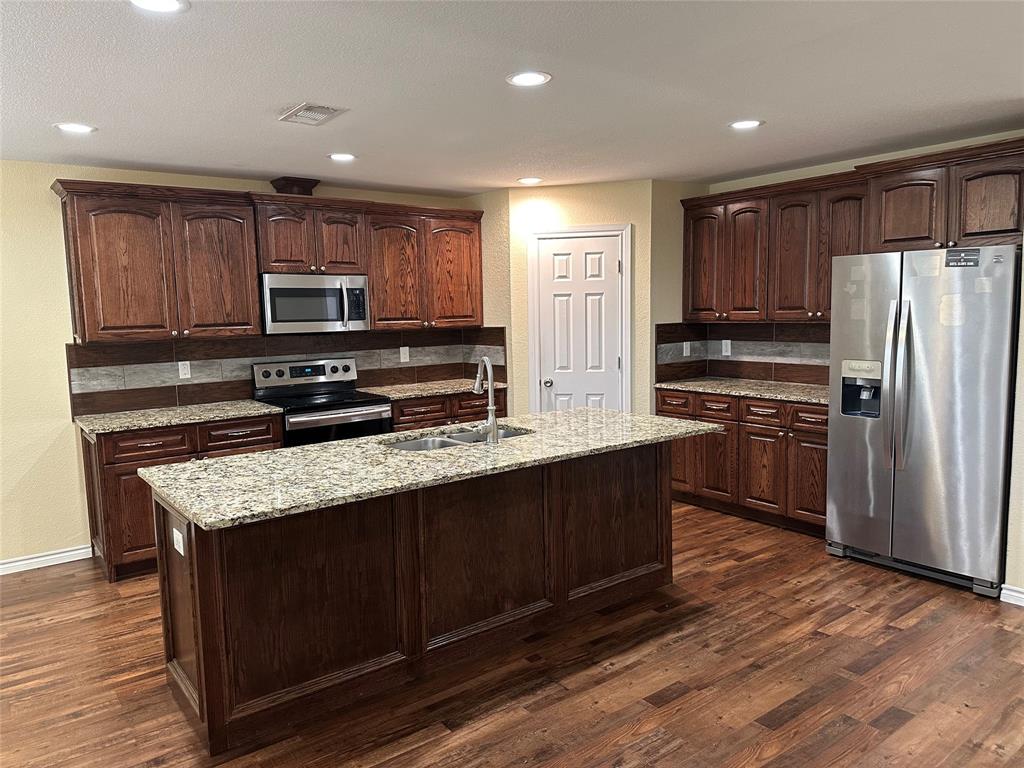 412 South Park Street Terrell, TX 75160 - Photo 8 of 15 a kitchen with kitchen island wooden cabinets a refrigerator and a sink