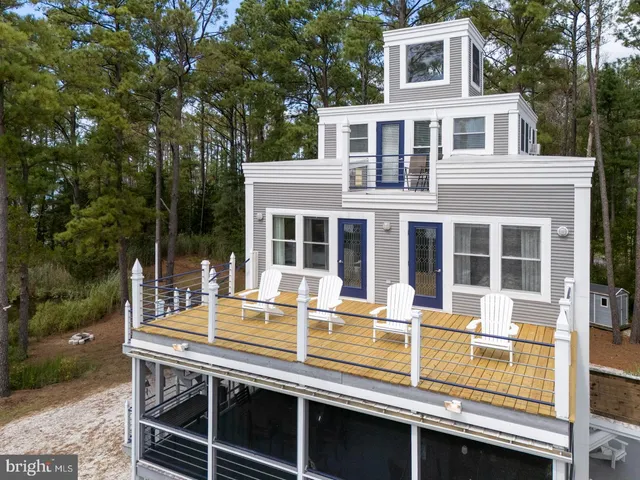 a view of a house with a deck and a dining table under an umbrella