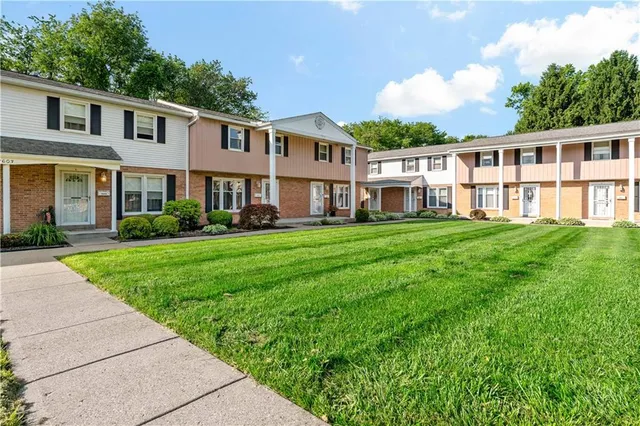 a front view of a house with a garden and trees