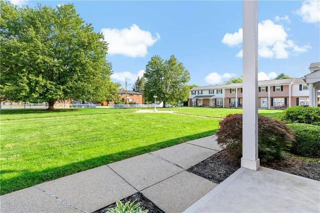 a view of a white house with a big yard and potted plants