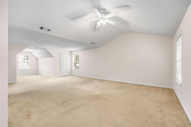 an empty room with a chandelier fan and windows