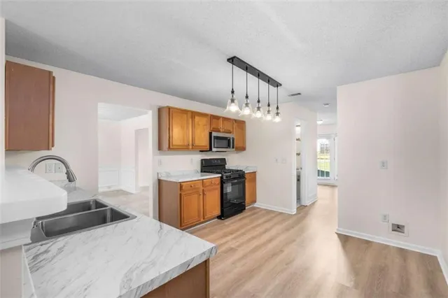 a kitchen with granite countertop a stove top oven a sink dishwasher a dining table and chairs with wooden floor