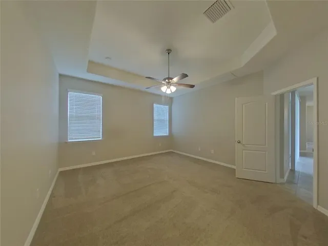 an empty room with a chandelier fan and windows