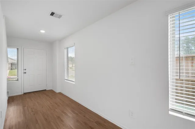 an empty room with wooden floor and windows