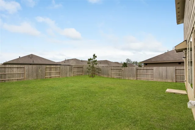 a view of a house with a yard and table and chairs under an umbrella