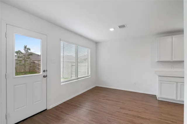 a view of an empty room with wooden floor and a window