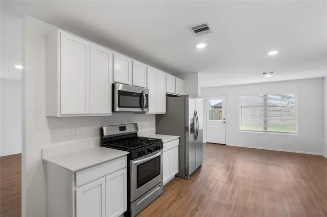 a kitchen with stainless steel appliances a stove a sink a refrigerator and white cabinets