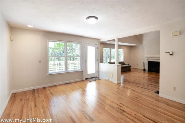 a view of empty room with wooden floor and window