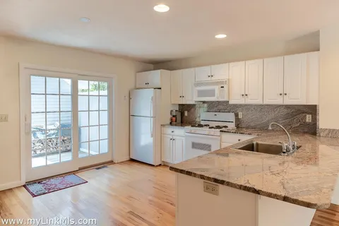 a kitchen with granite countertop white cabinets and refrigerator
