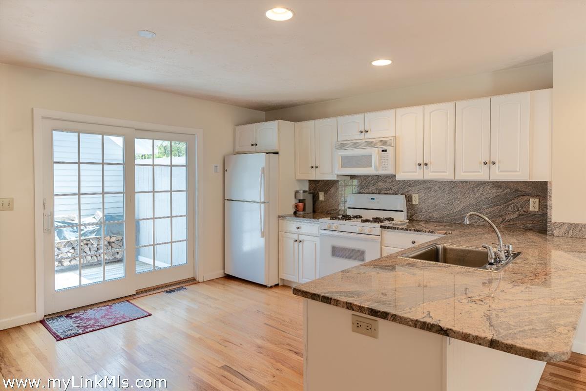 261 Sandpiper Lane, Unit 12 Vineyard Haven, MA 02568 - Photo 9 of 50 a kitchen with granite countertop white cabinets and refrigerator
