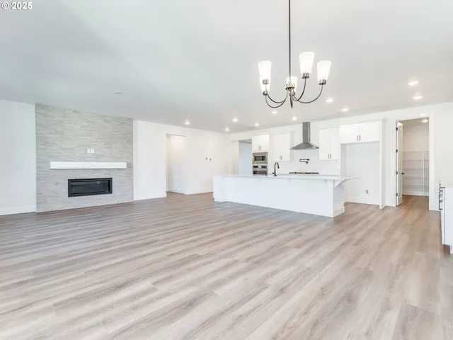 a large white kitchen with kitchen island a sink a refrigerator and white cabinets