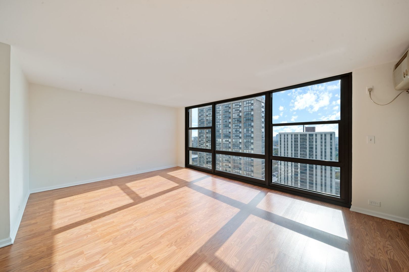 2605 South Indiana Avenue, Unit 2107 Chicago, IL 60616 - Photo 6 of 24 a view of an empty room with wooden floor and a window