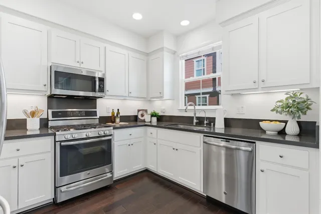 a kitchen with cabinets stainless steel appliances and wooden floor