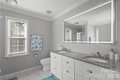 a bathroom with a granite countertop toilet sink and mirror