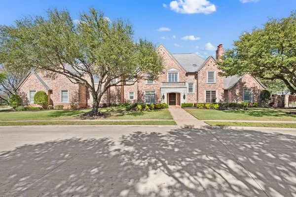 a view of big house with a big yard and large trees