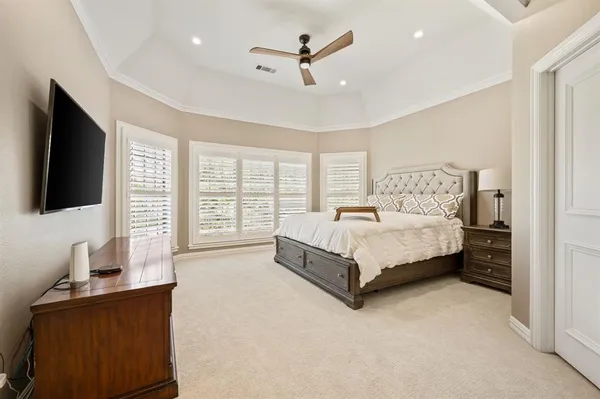 a bed sitting in a spacious bedroom next to a flat screen tv with a large window