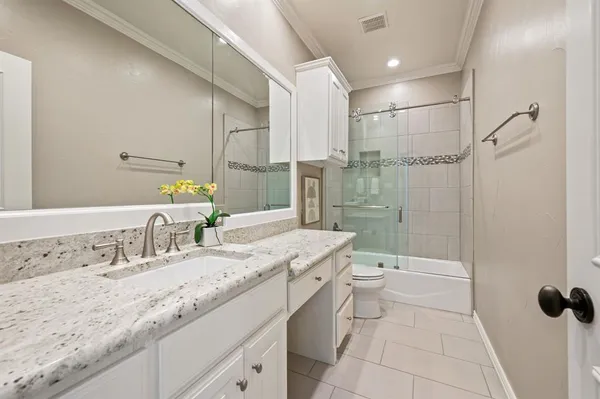 a bathroom with a granite countertop sink a toilet and shower