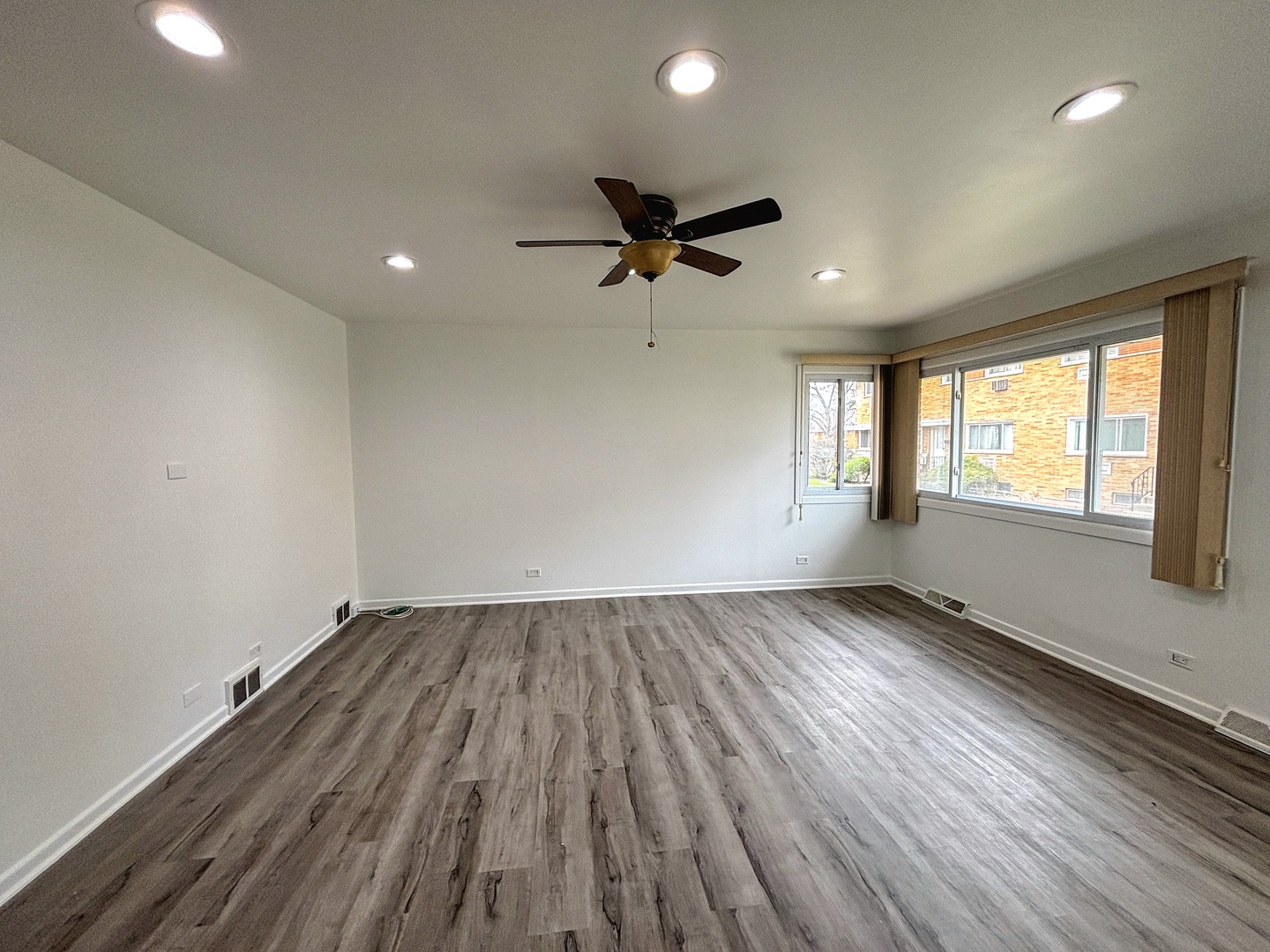 8664 Gregory Lane, Unit E Des Plaines, IL 60016 - Photo 3 of 15 an empty room with wooden floor ceiling fan and windows