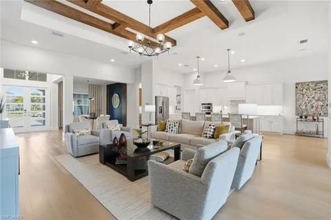 a living room with furniture kitchen view and a chandelier