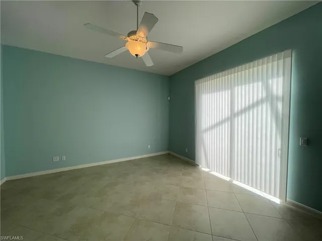 an empty room with a chandelier fan and window