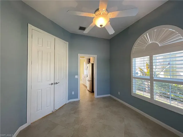 an empty room with windows and chandelier fan