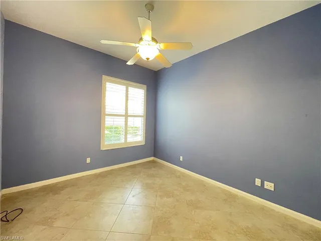an empty room with a chandelier fan and windows