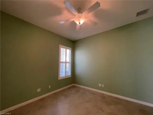 an empty room with a window and a fan