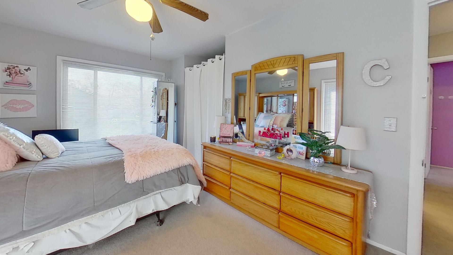 772 Colorado Court, Unit 772 Carol Stream, IL 60188 - Photo 19 of 26 a bedroom with a bed lamp and a large mirror on the dresser