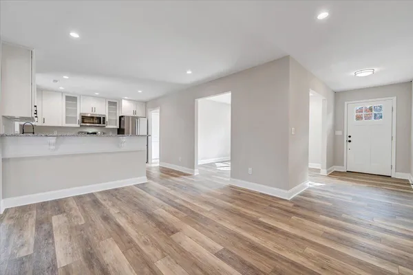 an empty room with wooden floor fan and windows