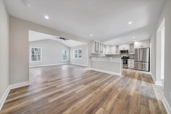 a view of an empty room with wooden floor and a window