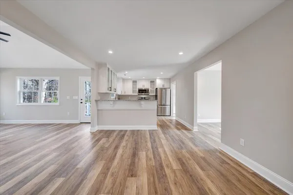 a view of an empty room with window and wooden floor