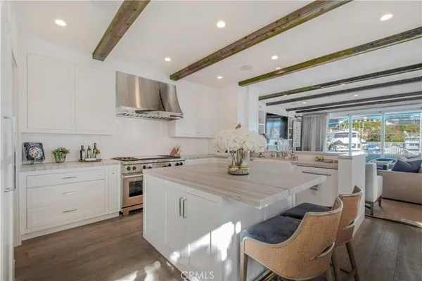 a kitchen with stainless steel appliances granite countertop a stove top oven a sink a dining table and chairs with wooden floor