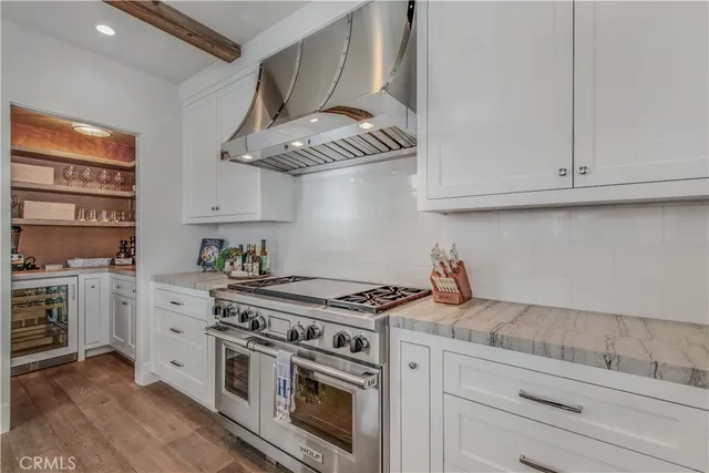a white kitchen with stainless steel appliances granite countertop a stove and a white cabinets