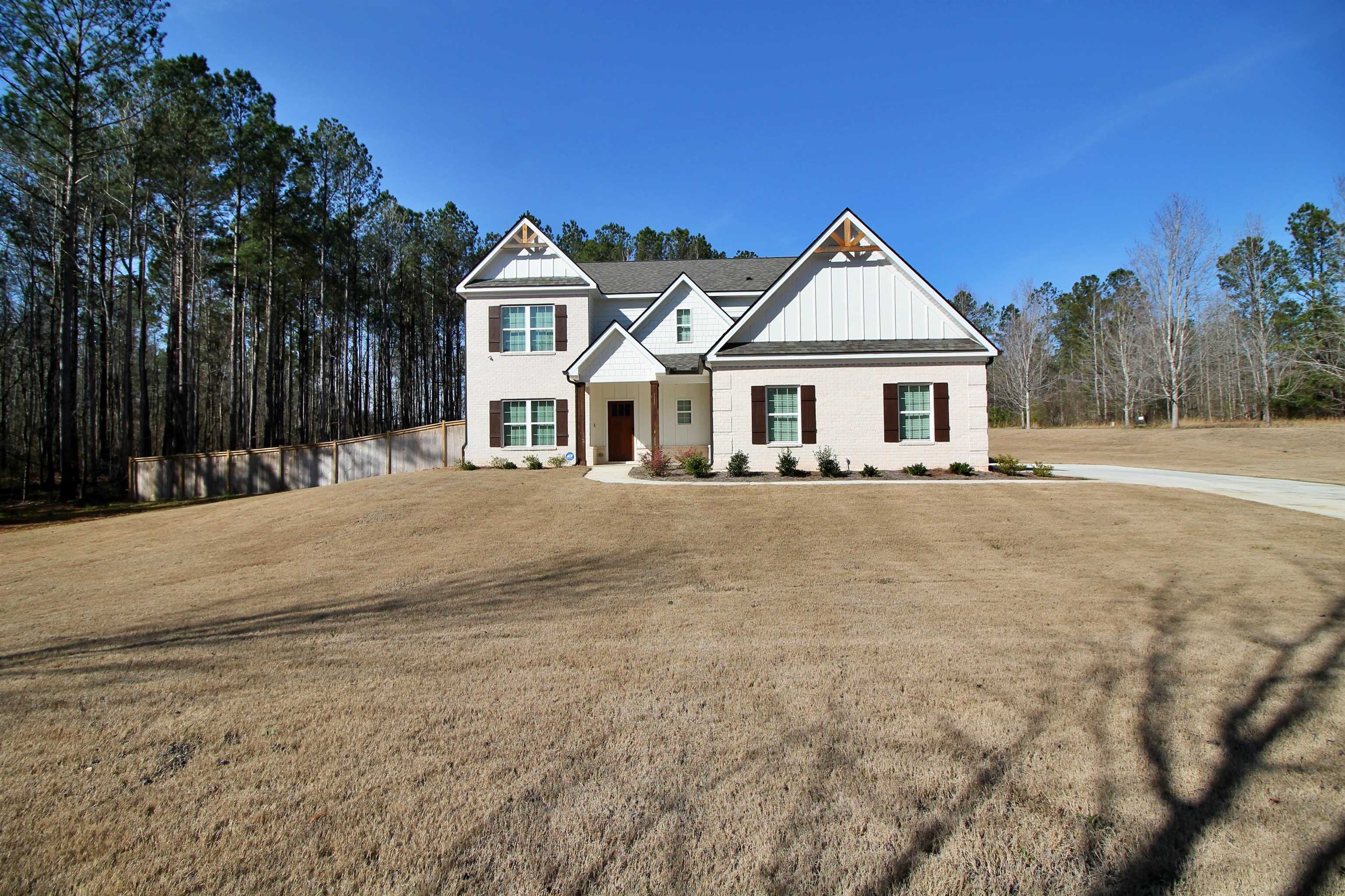 a front view of a house with a yard covered with snow and trees