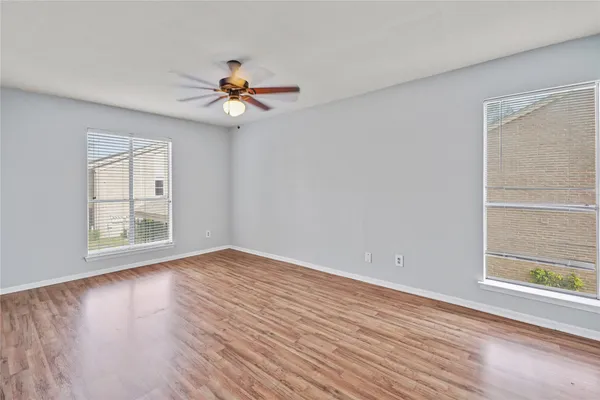 a view of empty room with wooden floor and fan